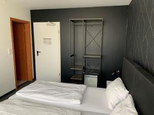 a bedroom with a white bed with a black wall at MOTELO Bielefeld - Smart HOTEL in Bielefeld