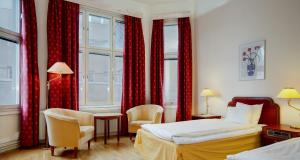 um quarto de hotel com duas camas e cortinas vermelhas em First Hotel Stadt em Härnösand