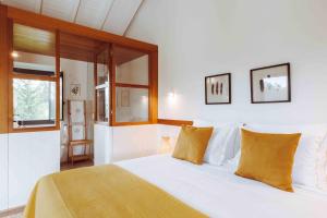 um quarto com uma cama com lençóis brancos e almofadas amarelas em Oliveiras Village — Agroturismo em Amarante