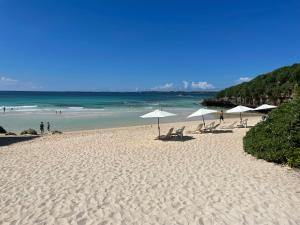 a beach with umbrellas and chairs and the ocean at BiBi Hotel 宮古空港前 in Miyako-jima