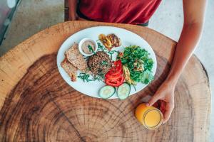 una persona sosteniendo un plato de comida en una mesa en Iluminar Beachfront Suites, en Nosara