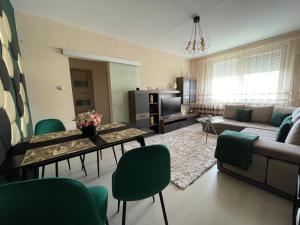 uma sala de estar com um sofá, uma mesa e cadeiras em Bella Apartman Debrecen em Debrecen