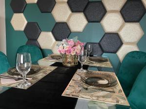 einen Tisch mit Tellern, Gläsern und Blumen darauf in der Unterkunft Bella Apartman Debrecen in Debrecen