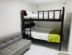 1 dormitorio con 2 literas y sofá en Confort Home - Apartamento ¨Dalias¨, en Baños