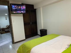 1 dormitorio con 1 cama y TV de pantalla plana en Confort Home - Apartamento ¨Dalias¨, en Baños