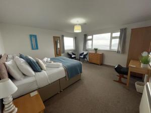 a hotel room with a bed and a desk and chairs at Sea Spirit - Sweeping Sea Views first floor spacious modern apartment in Looe- with FREE parking! in Looe