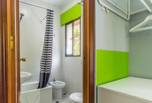 a green and white bathroom with a toilet and a sink at Hostal Tropical in Almuñécar
