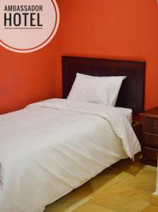 1 cama con edredón blanco y pared de color naranja en Hotel Ambassador, en Quito