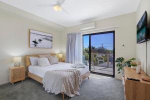 - une chambre avec un lit et une porte coulissante en verre dans l'établissement La Vida on Anzac, à Redcliffe