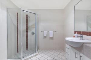 a white bathroom with a shower and a sink at La Vida on Anzac in Redcliffe