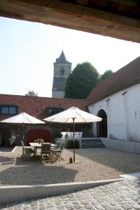 een patio met tafels en parasols en een klokkentoren bij B&B Hof ter Kwaremont in Kluisbergen