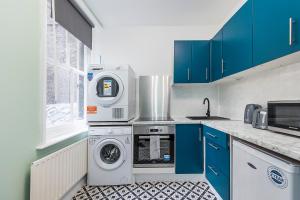 a kitchen with blue cabinets and a washer and dryer at Verv Brick Lane in London