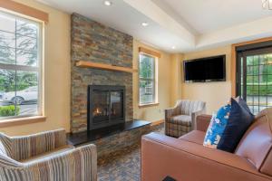 a living room with a fireplace and two chairs at Best Western Plus Columbia River Inn in Cascade Locks