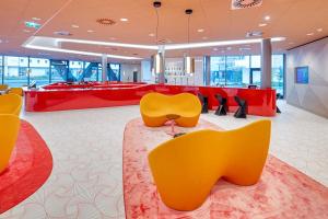 a lobby with yellow chairs and a red counter at prizeotel Vienna-City in Vienna