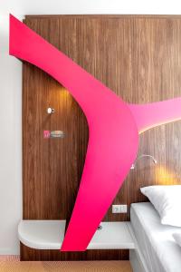 a bedroom with a pink ribbon on the wall at prizeotel Vienna-City in Vienna