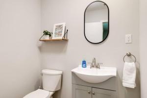 a bathroom with a toilet and a sink and a mirror at Charming, Cheerful 3 Bedroom Home in Richmond, VA! in Richmond +41 photos