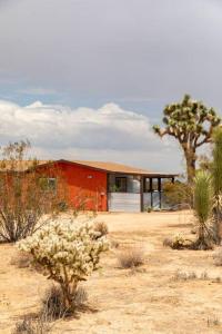 una casa roja en medio del desierto en Cryptic Cabin-Tranquil Bohemian Getaway w/Hot Tub, en Yucca Valley