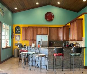 a kitchen with wooden cabinets and bar stools at Private Oceanfront Escape: Kayaks, Sunsets, Coral! in Hope Estate