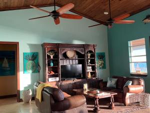 a living room with couches and a tv at Private Oceanfront Escape: Kayaks, Sunsets, Coral! 