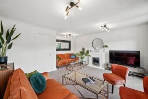 a living room with orange furniture and a fireplace at Townhouse in Dartford sleeps 8 with free parking in Dartford