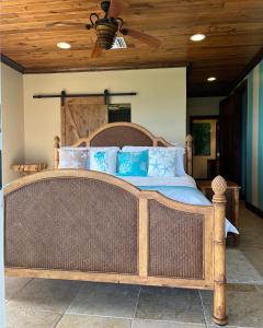 a bedroom with a large wooden bed with blue pillows at Private Oceanfront Escape: Kayaks, Sunsets, Coral! 
