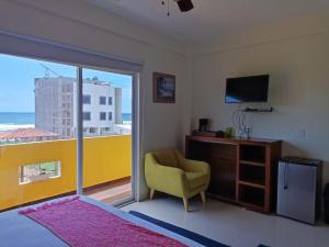 1 dormitorio con TV, silla y ventana en Hotel Happy Beach en Zihuatanejo