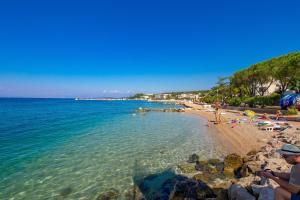 a beach with people laying on the sand and the water at Apartments with a parking space Malinska (Krk) - 5289 in Malinska