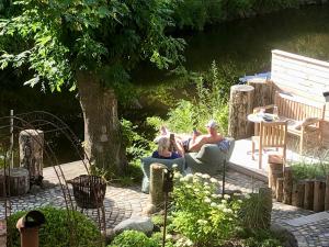 twee mensen zitten in stoelen in een tuin bij Knuffelkamer über der Gracht in Friedrichstadt