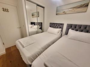 2 bedden in een kleine kamer met een spiegel bij City Centre Stylish Apartment Croydon-Free Parking Provided in Croydon