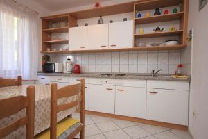 a kitchen with white cabinets and a table at Apartments by the sea Okrug Gornji, Ciovo - 8441 in Trogir
