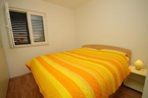 een geel en oranje gestreept bed in een slaapkamer bij Apartments by the sea Stari Grad, Hvar - 8704 in Stari Grad