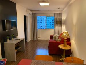 a living room with a red couch and a table at Flat Ipanema 2 Quadras da Praia - Estacionamento gratuito in Rio de Janeiro