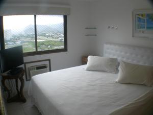 Schlafzimmer mit einem Bett mit weißer Bettwäsche und einem Fenster in der Unterkunft Dolce Vita Residence in Rio de Janeiro