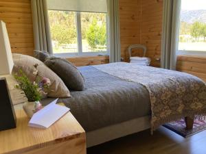 a bedroom with a bed, a desk and a window at Hostal Vuelta al Sur in Cochamó