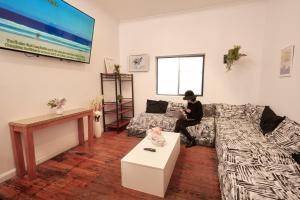 a person sitting on a couch in a living room at PodBed Coogee Beachside in Sydney