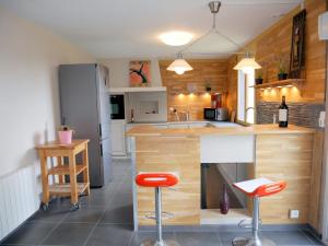 une cuisine avec un comptoir et deux tabourets de bar rouge dans l'établissement Cottage, Guisseny, à Guissény