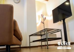 a flat screen tv on a glass stand next to a chair at GLOCE 鎌倉 若宮大路House お部屋から江ノ電ビューを独り占め 鎌倉駅から徒歩3分 in Kamakura