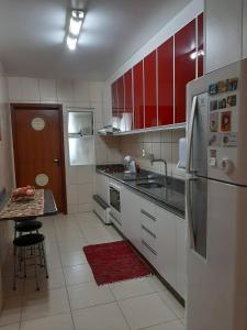 una cocina con electrodomésticos blancos y armarios rojos en Apê aconchegante e quentinho em São Joaquim en São Joaquim