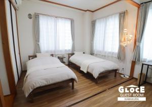 two beds in a room with windows and wooden floors at GLOCE 鎌倉 若宮大路House お部屋から江ノ電ビューを独り占め 鎌倉駅から徒歩3分 in Kamakura