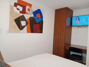 Hotel Posada de Santa Elena في تونخا: غرفة نوم بسرير وكابينة وتلفزيون