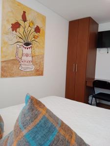 Un dormitorio con una foto de un jarrón con flores. en Hotel Posada de Santa Elena, en Tunja