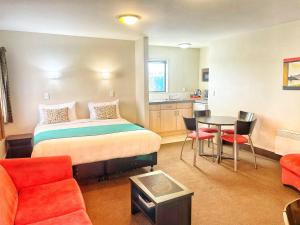 a hotel room with a bed and a table and chairs at Bella Vista Motel Ashburton in Ashburton