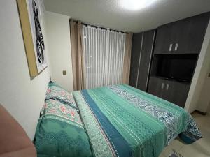 1 dormitorio con 1 cama con edredón y almohadas verdes en Fantástico departamento a pasos de playa cavancha con estacionamiento en Iquique