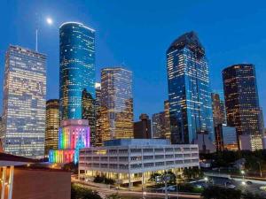 un profilo della città con grattacieli alti di notte di Gorgeous Apartment. Montrose / Downtown a Houston