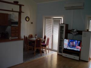 eine Küche und ein Esszimmer mit einem Tisch und einem TV in der Unterkunft Apartments with a parking space Pinezici, Krk - 15269 in Vrh