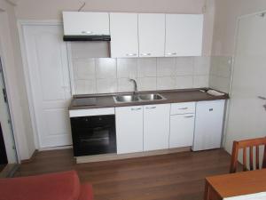 eine kleine Küche mit weißen Schränken und einem Waschbecken in der Unterkunft Apartments with a parking space Kornic, Krk - 15293 in Kornić