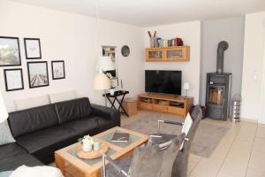 a living room with a black couch and a tv at Grachtenkate in Greetsiel
