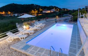 a swimming pool with chairs and a table and a table at Family friendly apartments with a swimming pool Bacina, Neretva Delta - Usce Neretve - 15309 in Ploče