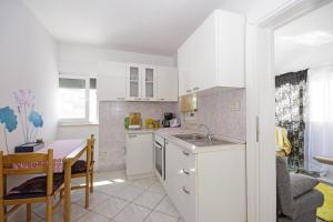 een keuken met witte kasten, een tafel en een wastafel bij Holiday house with WiFi Trogir - 15319 in Trogir