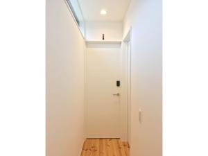 um corredor com uma porta branca e um piso de madeira em Minshuku Kakutani Hitohira - Vacation STAY 16023v em Wada